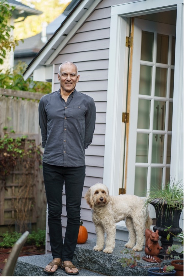 Moungi Bawendi, casually dressed, stands on the steps outside his home. His dog Phoebe poses next to him, proud of her human.