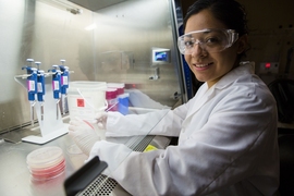 Mariana Matus working in a lab, wearing white lab coat and goggles