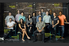 Photo of a dozen or so people in front of a brick wall