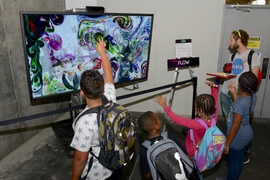 Several Innovation Playground attendees experience an MIT-designed interactive art piece, Flow, created by MIT alumnus Karl Sims.