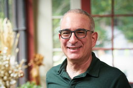 Portrait photo of Joshua Angrist at his home, standing in front of a window