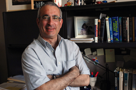 Portrait photo of Joshua Angrist standing in front of a bookshelf