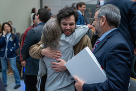 Kornbluth, with her back to the camera, is hugged by her son, Alex, while her husband, Daniel Lew, looks on from the side.