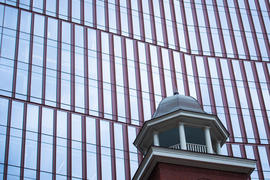 Alt text: Photo shows the repeated, long rectangular windows of Building E-28 on 314 Main Street. In the foreground, the ornamental dome-like top of the Kendall hotel appears on the bottom right.