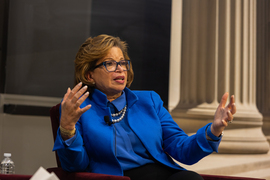 Valerie Jarrett gestures with her hands, with a blackboard in background.