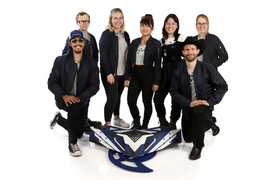 The Valkyrie team, dressed in black, gray, and white, poses with their blue and white robot in the center.