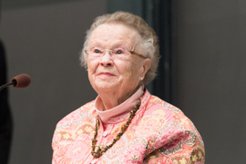 Priscilla King Gray portrait as she speaks at a podium with gray background.