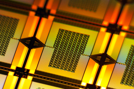 A yellow-lit closeup zooms in on one tiny, rectangular amplifier on the wafer. It has a chain-like rectangular grid in center that connects to the left and right edges of the wafer.