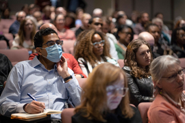 Ghachem wears a mask and is seated in the packed audience while watching the event.