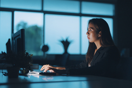 A woman working at a computer sitting at desk.