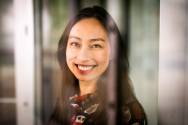 Closeup of Ho as she smiles through a widow with blurry reflections.