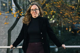 Megan Black poses for portrait with autumn trees in background.