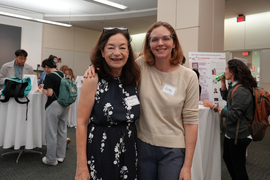 Nancye Mims, left, and Kirsty Bennett pose for a photo during the celebration. People eat at tables in background.