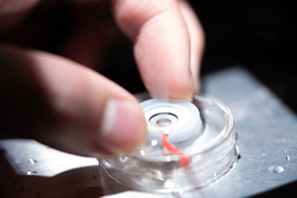 Close-up photos shows fingers manipulating a little valve. Steam emerges from the valve.