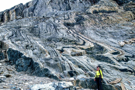 Athena Eyster stands in the corner, with a huge rock formation in background that has wavy black and white stripes.