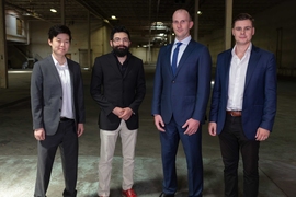 Four people in suits stand for a photo